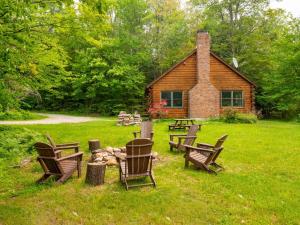 a group of chairs sitting in the grass in front of a cabin at Berkshire Vacation Rentals: Private Cabin On Over 12 Acres Of Woods in Becket