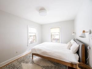 a white bedroom with a bed and two windows at Berkshire Vacation Rentals: Chic Pittsfield Home With A View in Pittsfield