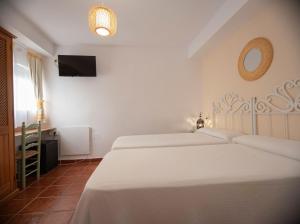a bedroom with two beds and a television in it at Hostal San Juan in Salobreña