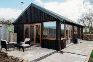 a black house with glass doors and a patio at Woodpecker Lodge- A Pet Friendly Rural Retreat in Callington