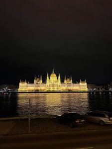 un gran edificio con luces en el agua por la noche en Parliament view Premium Apartment en Budapest