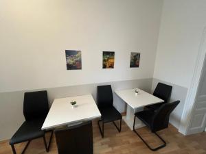 two tables and chairs in a room with paintings on the wall at Paky Appartements 00210 in Vienna