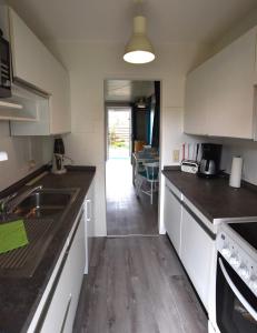 Bungalow "Ostseehus" في Grömnitzerhagen: مطبخ مع خزائن بيضاء وقمم منضدة سوداء +3 صور