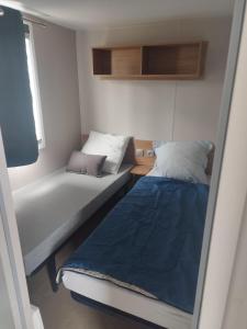 Una pequeña habitación con dos camas y una ventana. en Mobil-home bord de mer, en Colleville-sur-Mer