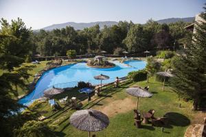 una piscina con sombrillas y sillas en un complejo en Hotel Doña Teresa en La Alberca