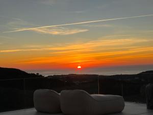 een balkon met een bank en uitzicht op de zonsondergang bij Exclusive VILLA IMAGINE MARBELLA breathtaking panoramic sea views heated infinity pool in Benahavís +37 foto's