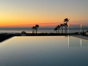 een groot zwembad met een zonsondergang op de achtergrond bij Exclusive VILLA IMAGINE MARBELLA breathtaking panoramic sea views heated infinity pool in Benahavís