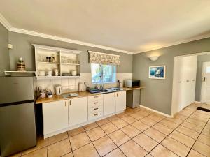 eine Küche mit weißen Schränken und Fliesenboden in der Unterkunft Charming Guest Suite in the Constantia Wine Valley in Kapstadt