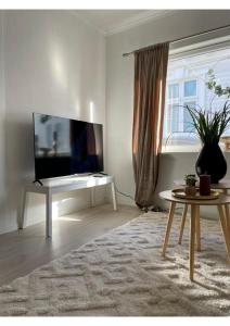 un soggiorno con TV a schermo piatto e tavolo di Koselig leilighet i hjertet av Flekkefjord a Flekkefjord