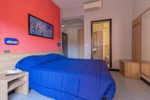 a bedroom with a blue bed and a red wall at Abc Hotel in Rimini