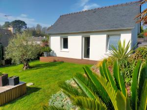 a white house with a yard with green grass at La chambre de KERLAGATU in Quimper