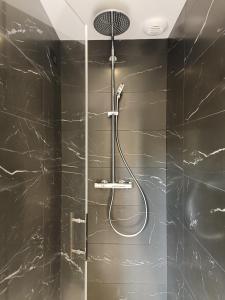 La salle de bains est pourvue d'une douche et de murs en marbre noir. dans l'établissement KERLAGATU, à Quimper