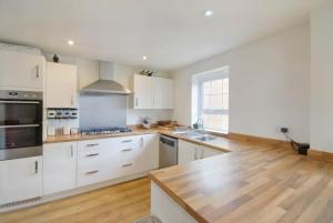 uma cozinha com armários brancos e piso em madeira em Cozy Casa: A Home Away from Home 