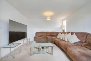 a living room with a brown couch and a tv at Cozy Casa: A Home Away from Home 