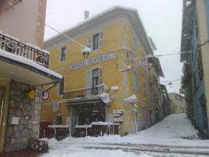 a snow covered street with a yellow building at Hotel Central in Saint-Pierre-dʼAlbigny