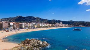 a beach with people and a boat in the water at Apartament Mar Beach Lloret in Lloret de Mar
