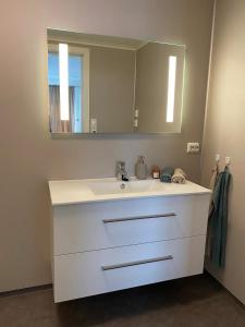un bagno con un lavandino bianco e uno specchio di Koselig leilighet i hjertet av Flekkefjord a Flekkefjord Altre 2 foto
