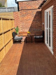 a patio with two chairs and a table on a brick wall at Exclusive Lakeside Apartment in Grays Thurrock