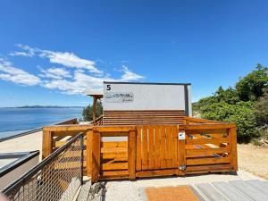 eine Holzbank auf einer Terrasse mit Blick auf das Wasser in der Unterkunft d-view Premium Mobile Home - panoramic seaview - 150 m from beach, free parking in Drage