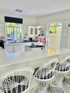 a kitchen with a white counter with four stools at Le Rock @ Calodyne in Grand Gaube