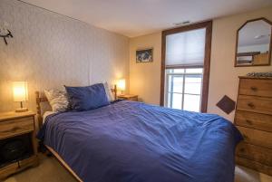 a bedroom with a blue bed and a dresser and a window at The Rose in Leadville