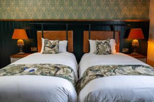 two beds in a hotel room with two lamps at Himley House by Chef & Brewer Collection in Himley