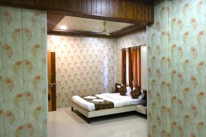 a bedroom with a bed in a room with wallpaper at Hotel Midtown Inn in Trimbak