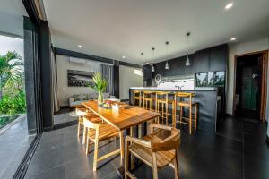 uma cozinha e sala de jantar com uma mesa de madeira e cadeiras em Balangan Beach Villa Freya Jimbaran em Jimbaran
