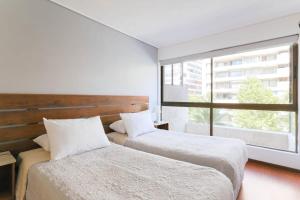 two beds in a room with a large window at Silver City with Parking & Wifi in Santiago