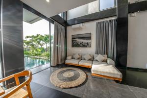 uma sala de estar com um sofá e uma piscina em Balangan Beach Villa Freya Jimbaran em Jimbaran