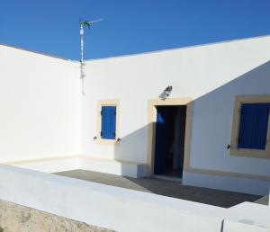 a white building with blue windows and a door at Sophie's Pourko House in Kythira