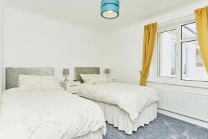 2 camas en un dormitorio blanco con ventana en Duver at the Aqua, en Shanklin