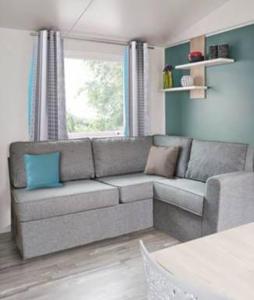 a living room with a gray couch and a window at Domaine de kerlann in Pont-Aven