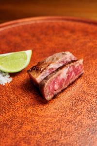 een stuk vlees op een bord met een kalk bij 湯の鶴迎賓館鶴の屋Tsurunoya in Yunotsuru