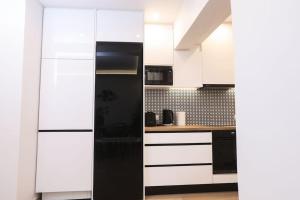 a kitchen with white cabinets and a black refrigerator at Venetian Canvas Retreat in Corfu