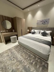 1 dormitorio con 1 cama grande y espejo en رنز بالاس للشقق الفندقية en Dammam