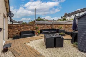 a patio with black furniture and a brick wall at 67 Midton Road in Prestwick