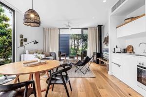 a kitchen and living room with a table and chairs at Luxury Villa 13 Within Bangalay in Shoalhaven Heads