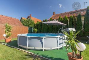 una piscina con sombrilla y plantas en un patio en Villa Eszter, en Balatonkeresztúr