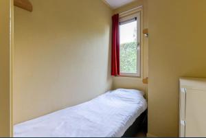 Kleines Zimmer mit einem Bett und einem Fenster in der Unterkunft Chalet de Vlotvaren in Wervershoof