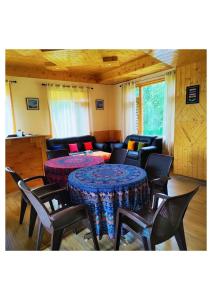 ein Zimmer mit 2 Tischen und Stühlen und einem Sofa in der Unterkunft Western Hill in Manali