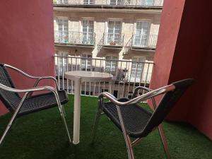 un balcón con 2 sillas y una mesa y un edificio en O balcón de Santo Domingo en Ourense