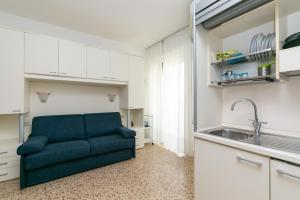 ein Wohnzimmer mit einer blauen Couch in einer Küche in der Unterkunft Luxemburg in Caorle