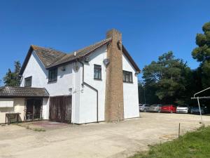 a white house with a brick chimney and a parking lot at Maylands - -Where memories are made. in Stanford le Hope
