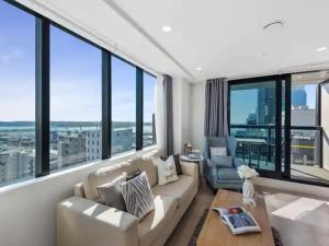 Una sala de estar con muebles blancos y grandes ventanales. en Sky Tower Views 2 Bed 2 Bath CBD Zodiak Stays, en Auckland