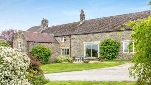 an exterior view of a stone house with a garden at Cara in Old Brampton