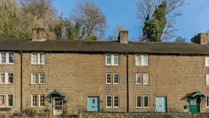 - un grand bâtiment en briques avec des portes et des fenêtres bleues dans l'établissement Calamine Cottage, à Cromford