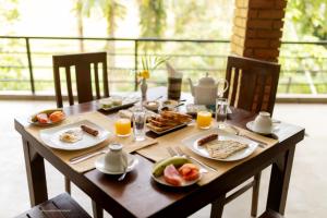 a wooden table with breakfast foods and orange juice at Eco Knuckles Holiday Lodge in Kandy