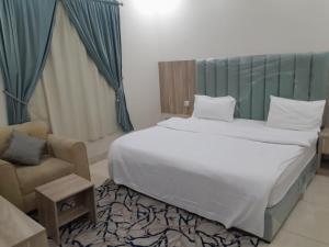 a bedroom with a large bed and a chair at دار الكيان للشقق المخدومة - Dar Al Kayan Serviced Apartments in Jeddah