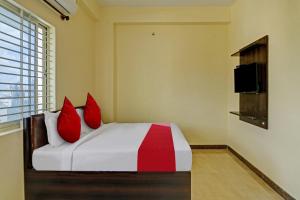 OYO Flagship Sri Chamundeshwari Boarding And Lodge في بانغالور: غرفة نوم بسرير ومخدات حمراء وتلفزيون